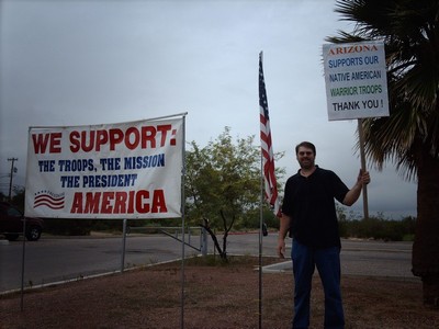 Wayne with sign 'Arizona Supports Our Native American Warrior Troops' and support banner at park entrance